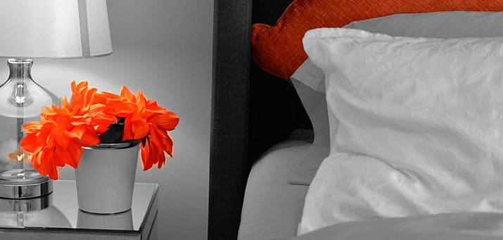 Professionelle Haushaltshilfe Stormarn sorgt für frische Blumen auf dem Nachttisch neben dem Bett.